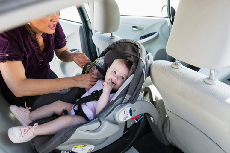 Mum placing baby in car seat