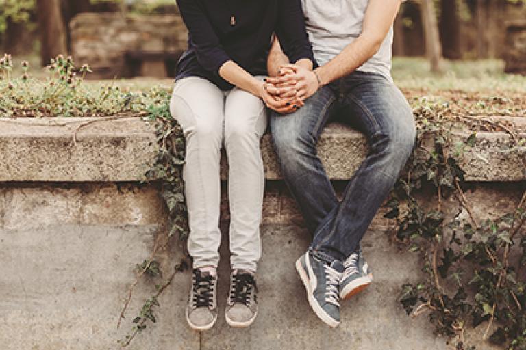 Couple sitting on wall holding hands