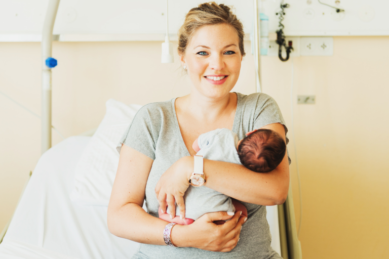 Mum with baby in her arms sitting on hospital bed