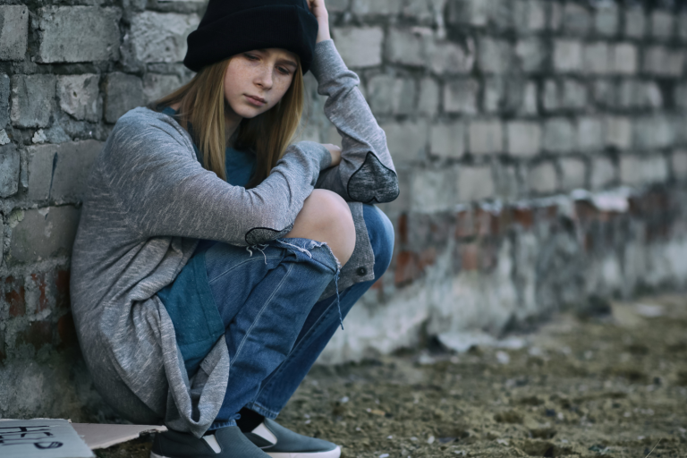 Teenage girl sitting against a wall