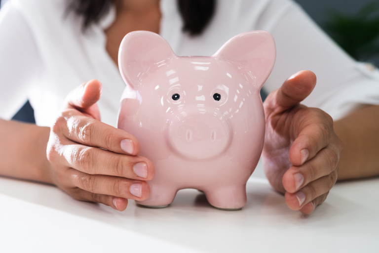 women holding hands around piggy bank