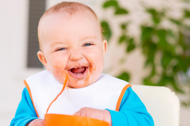 toddler eating with spoon and bowl