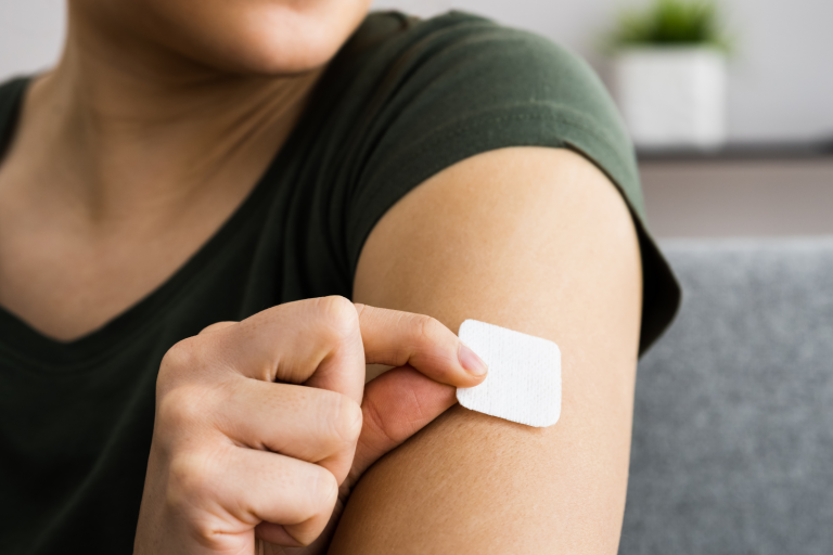 woman putting nicotine patch on arm