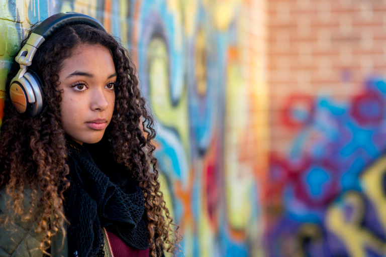 Teenage girl standing against a wall with graffiti