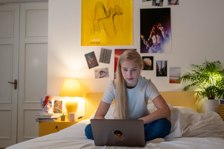 Girl on laptop on sitting on bed