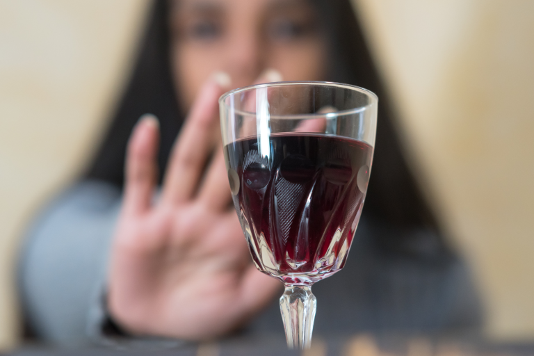 women reaching to glass of wine