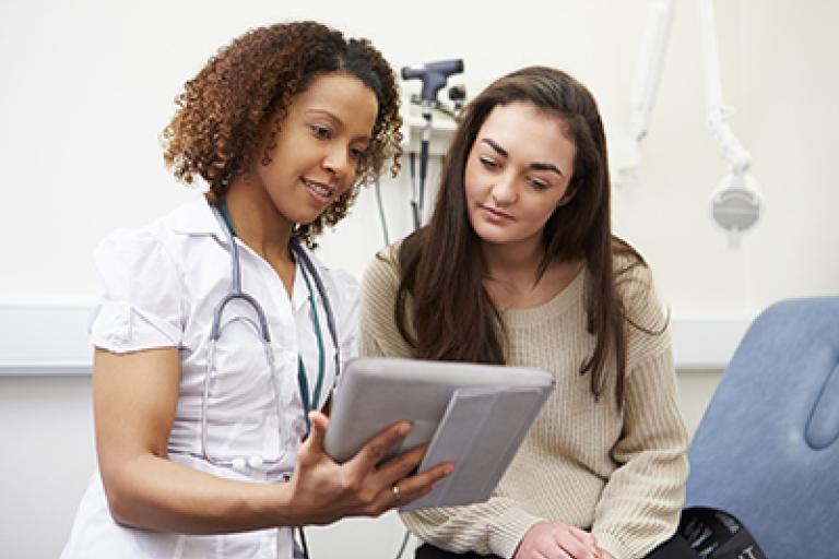 Nurse talking to lady looking at device