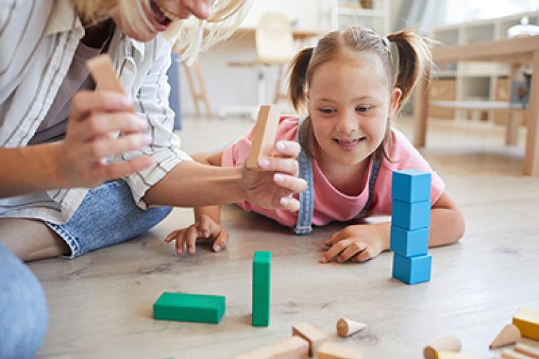 A parent/carer playing with blocks with their daughter who has SEN needs.