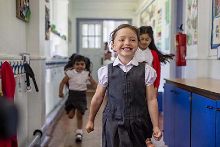 3 primary age children in their school hall smiling