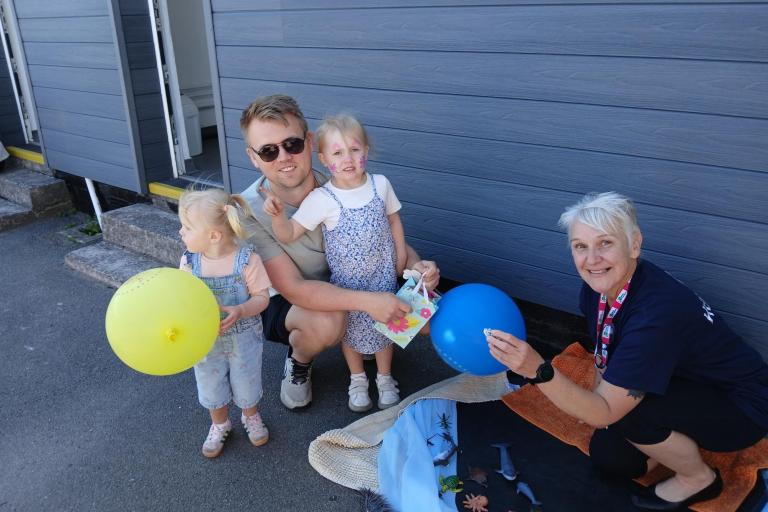 Staff handing balloons to two children