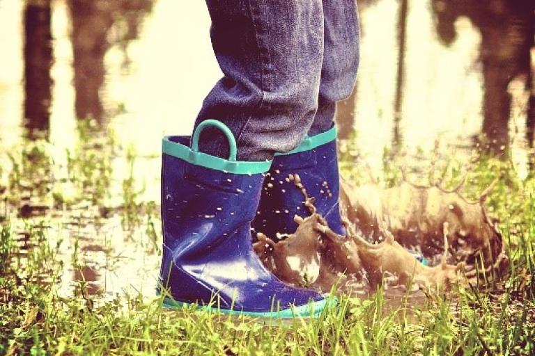 Child splashing in a puddle with wellies