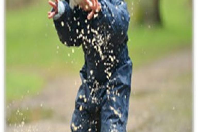 Child playing in the rain and puddle