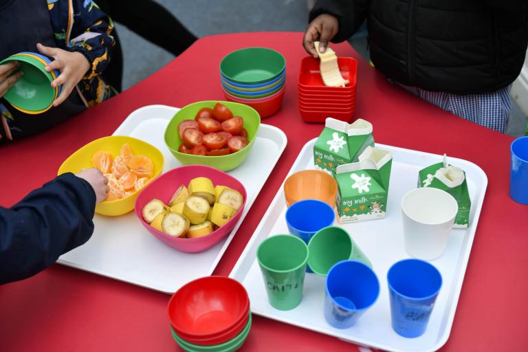 Children sat at a table eating fruit