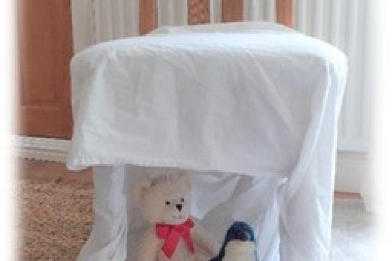 Sheet of paper across a chair, with toys underneath the chair