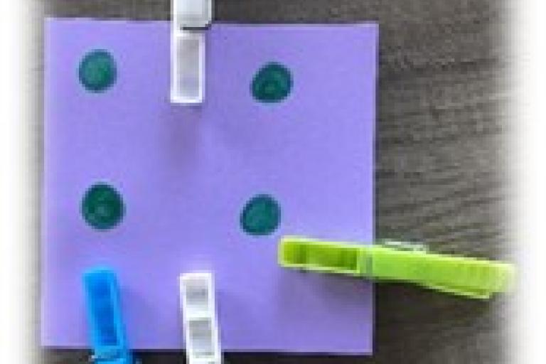Piece of coloured card with 4 spots. 4 pegs on the edge of the card.