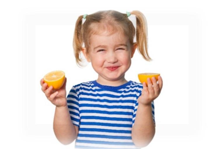Child holding up cut oranges in both hands.