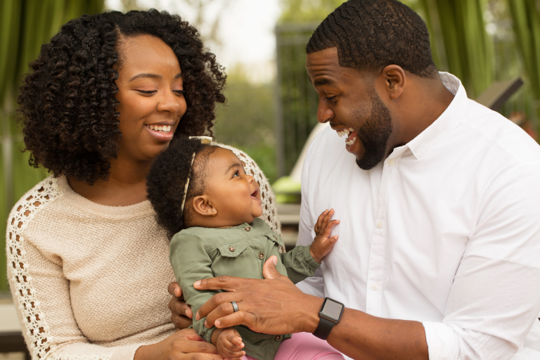 Baby looking up and smiling at adult