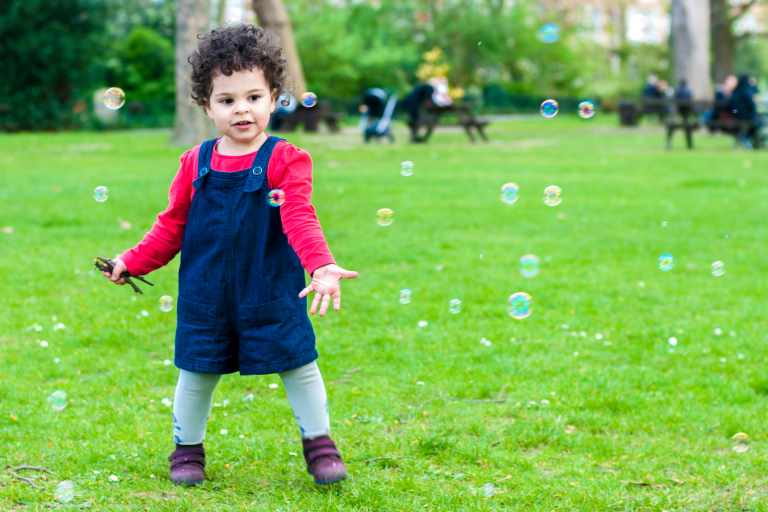 Child playing outside with bubbles