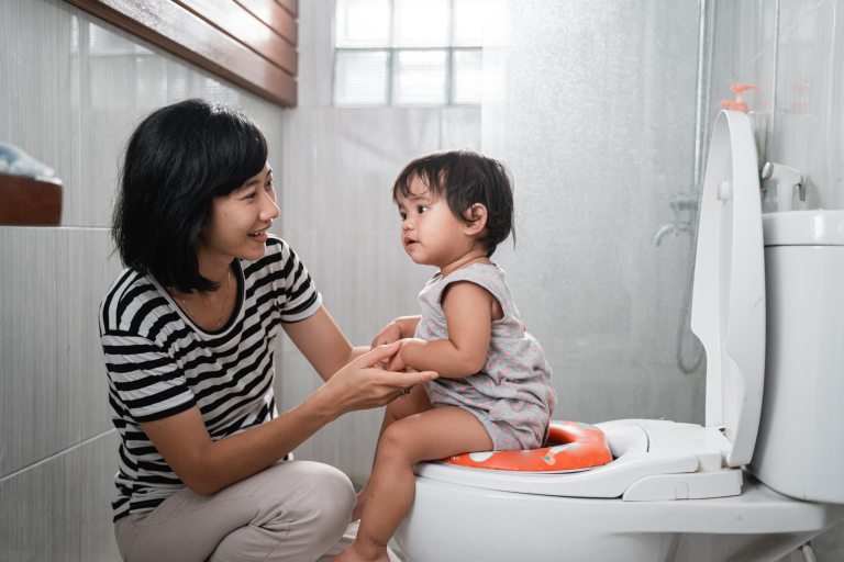 Child sat on a toilet with a adult holding them