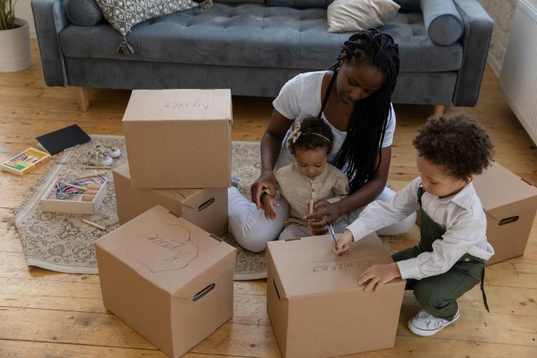 Adult with baby and toddler, drawing on cardboard boxes