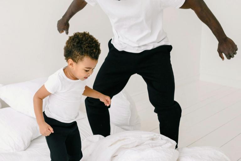 Adult and child jumping on the bed