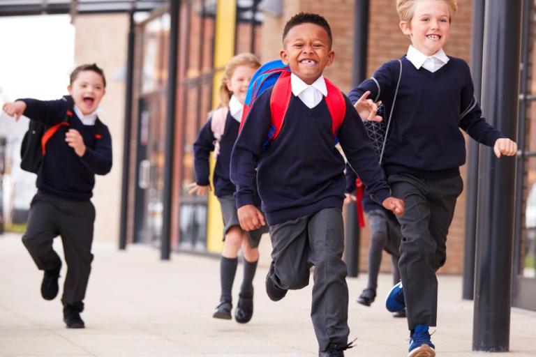 Children in school uniform running outside