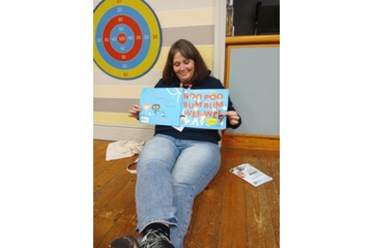 Adult sat on the floor holding a children's book