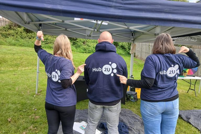 Three adults with Hub2U logo clothing