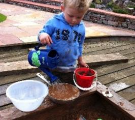 Child filling different sizes of containers with soil