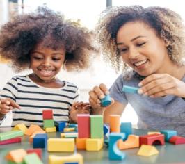 Adult and child playing with coloured wooden blocks