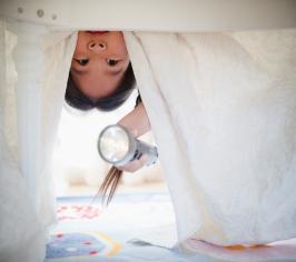 Child hanging upside, looking underneath the bed