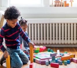 Two children playing with coloured blocks on the floor