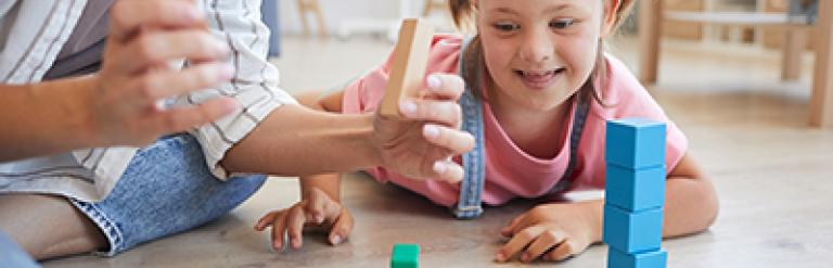 A parent/carer playing with blocks with their daughter who has SEN needs.