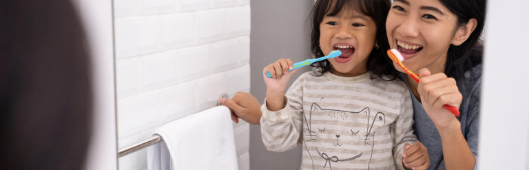 Adult and child brushing their teeth together
