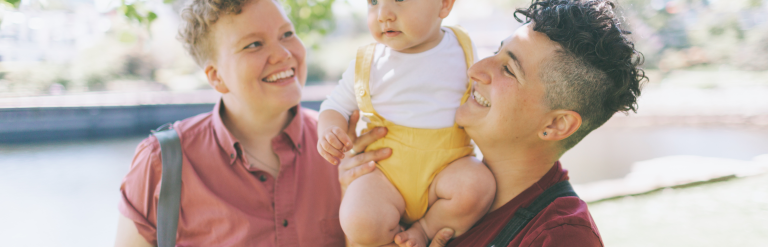 Adult holding up a child whilst another is smiling