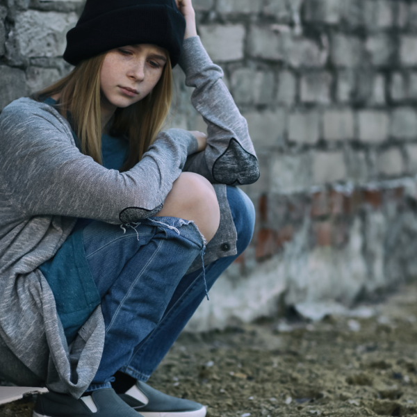 Teenage girl sitting against a wall