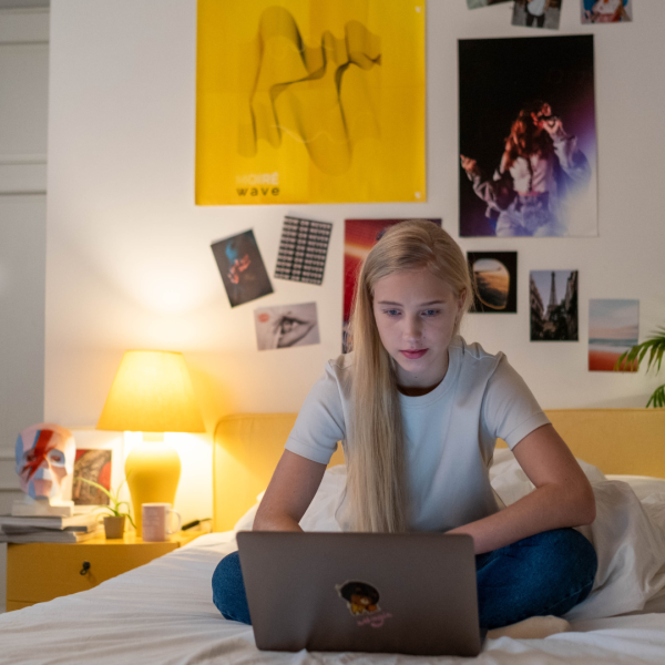 Girl on laptop on sitting on bed