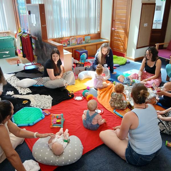Group of women sat on the floor with babies playing