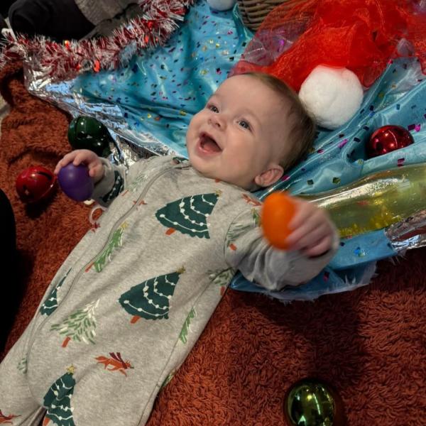 Baby in Christmas tree onesie looking excited